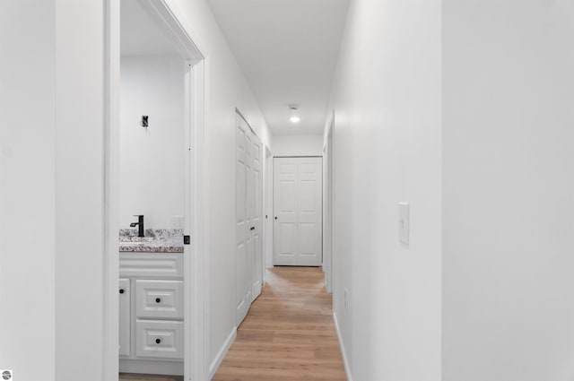 hall with light hardwood / wood-style floors and sink