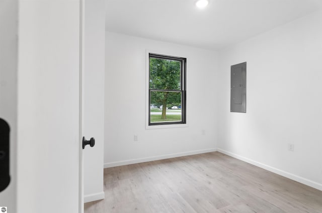 spare room with electric panel and light hardwood / wood-style floors