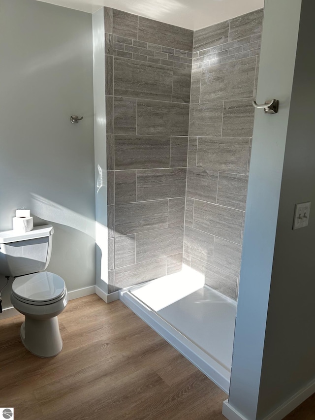 bathroom featuring tiled shower, toilet, and hardwood / wood-style floors