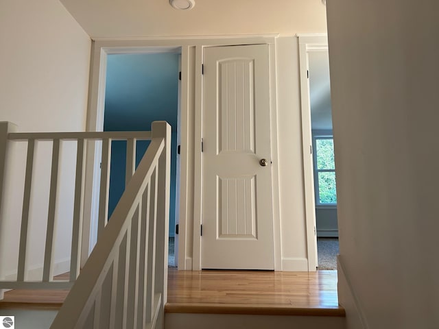 hallway with a baseboard heating unit and hardwood / wood-style floors