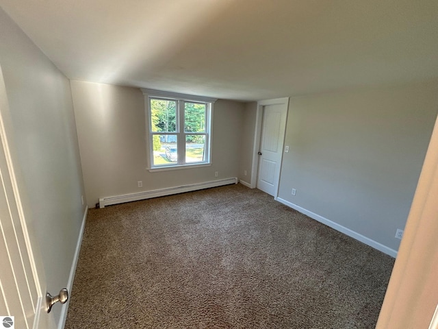 carpeted empty room featuring a baseboard heating unit