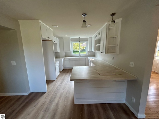 kitchen with hanging light fixtures, white cabinetry, wood-type flooring, and kitchen peninsula