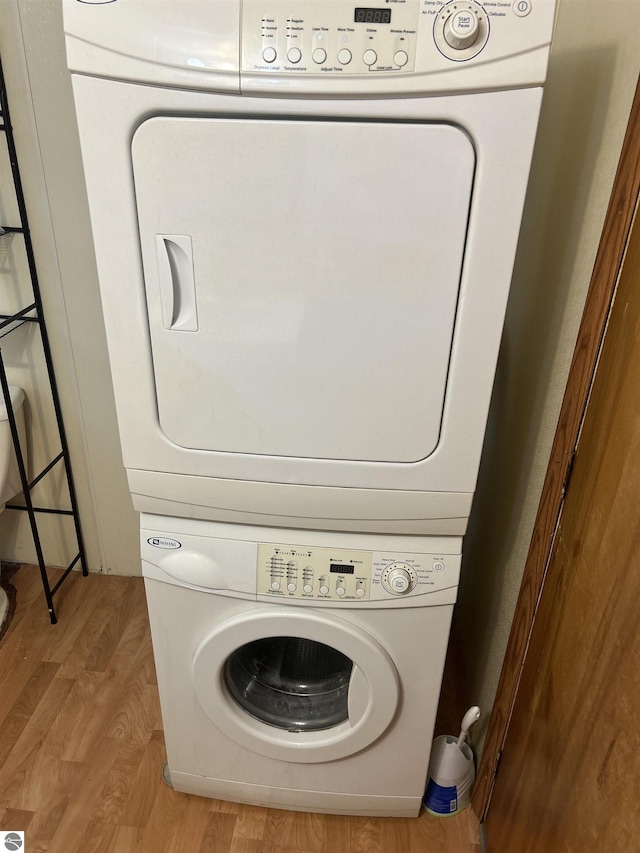 laundry room with light wood-type flooring and stacked washing maching and dryer