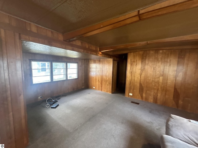 unfurnished room featuring wooden walls and beam ceiling