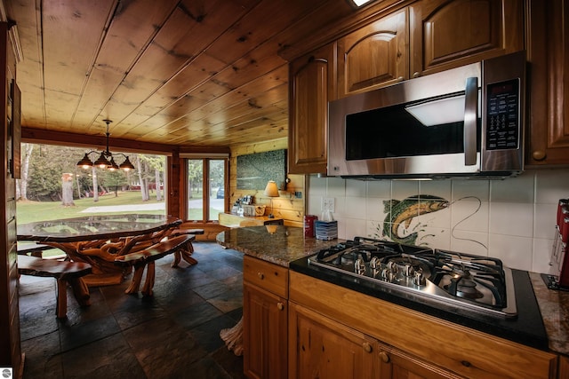 kitchen featuring a chandelier, hanging light fixtures, stainless steel appliances, wooden ceiling, and backsplash