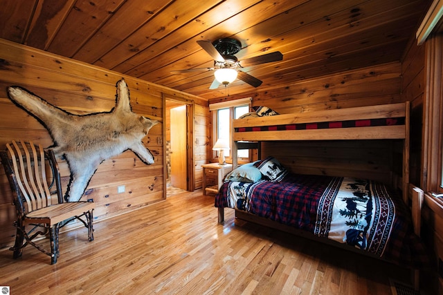 bedroom with light hardwood / wood-style floors, wood walls, and wood ceiling