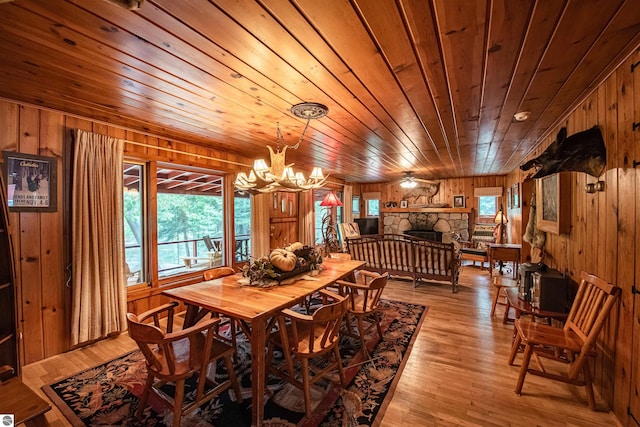 dining room with wood ceiling, light hardwood / wood-style flooring, wooden walls, and plenty of natural light