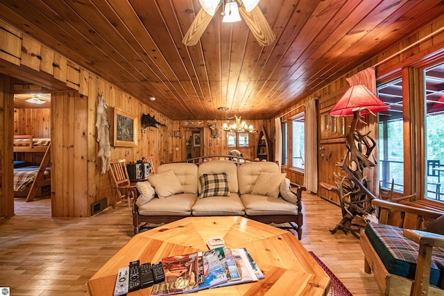 living room featuring ceiling fan with notable chandelier, wood walls, light hardwood / wood-style flooring, and wooden ceiling