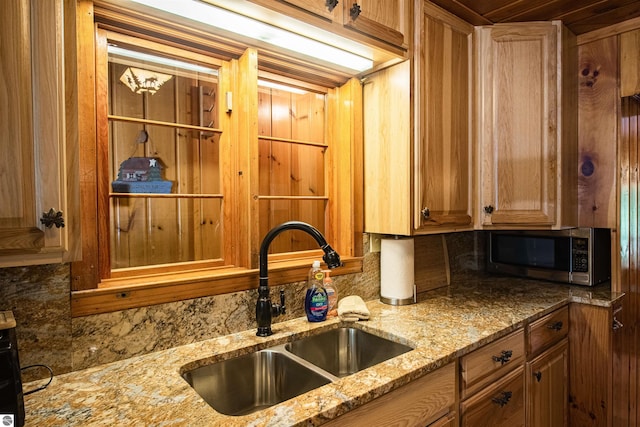 kitchen with sink, light stone counters, and backsplash