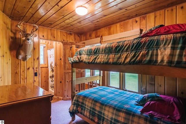 carpeted bedroom with wood walls and wooden ceiling