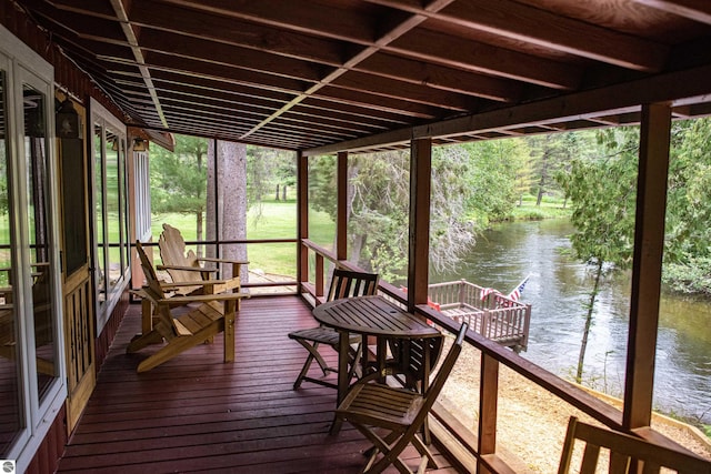 sunroom / solarium with a water view and a healthy amount of sunlight