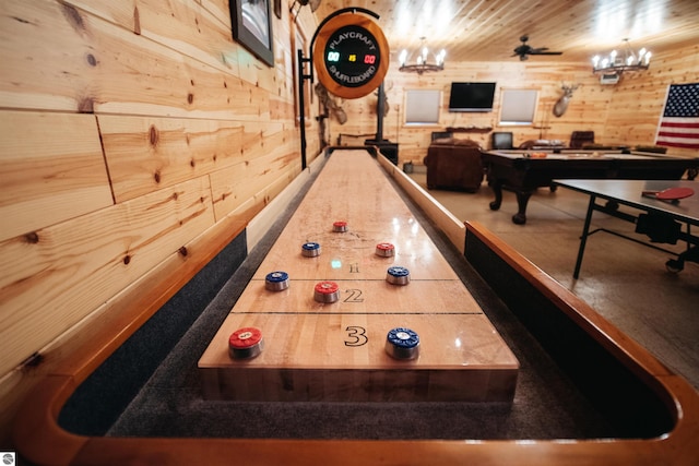 game room featuring a chandelier and wooden walls