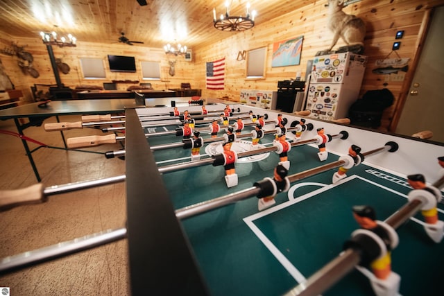 game room featuring wood ceiling, a chandelier, and wooden walls