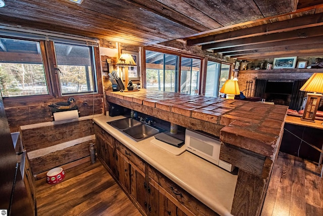 bar with hardwood / wood-style floors, sink, a brick fireplace, tile countertops, and wood walls