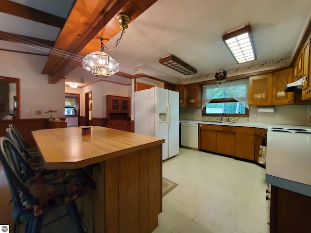 kitchen featuring white fridge with ice dispenser, dishwasher, hanging light fixtures, a kitchen breakfast bar, and sink