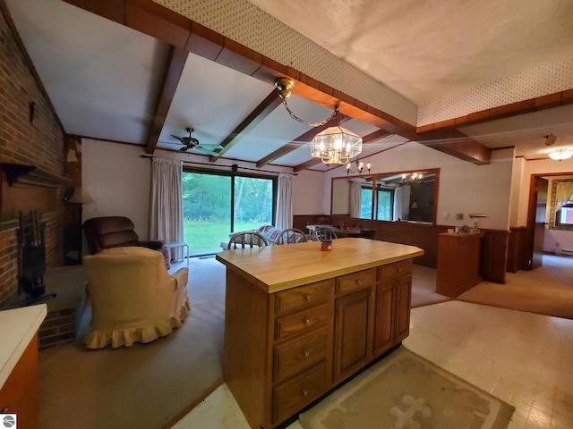 kitchen with beamed ceiling, a fireplace, ceiling fan with notable chandelier, and brick wall