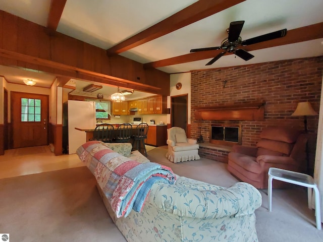 living room with ceiling fan, beamed ceiling, brick wall, carpet floors, and a brick fireplace