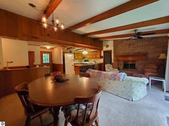 dining space featuring beamed ceiling, a fireplace, carpet, and ceiling fan with notable chandelier