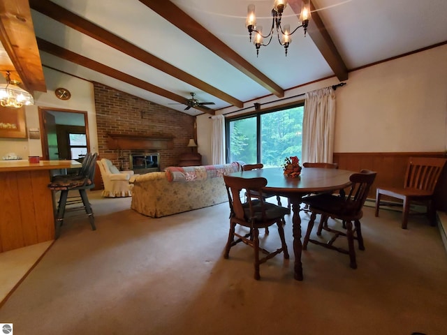 dining space with carpet flooring, ceiling fan with notable chandelier, lofted ceiling with beams, and a brick fireplace