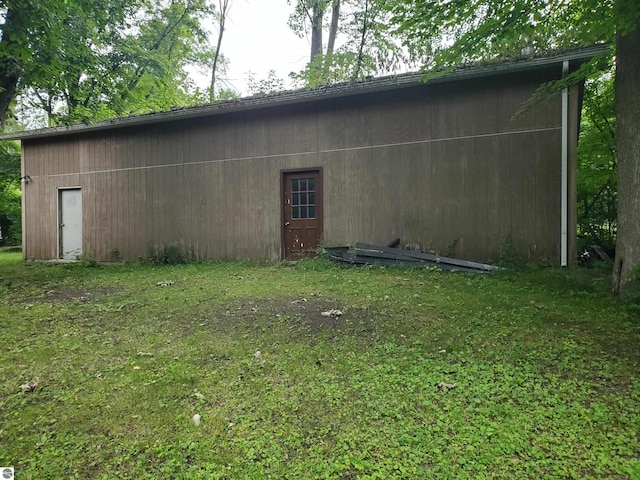 view of side of property with a lawn and an outbuilding