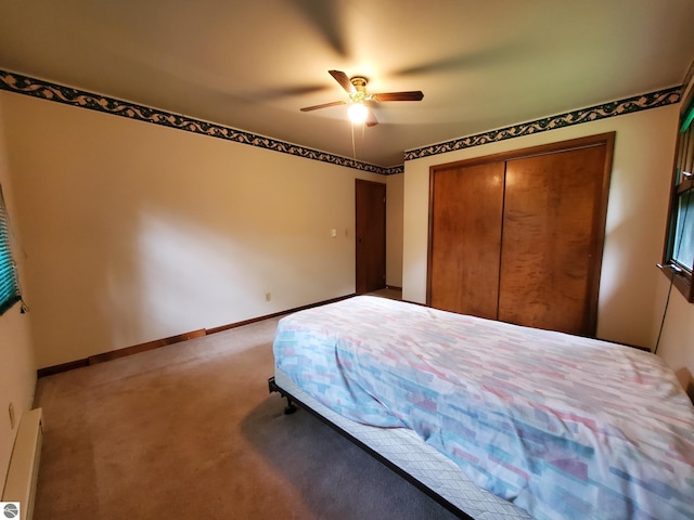 unfurnished bedroom with a closet, carpet, ceiling fan, and a baseboard heating unit