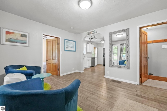 224 Saint Marys St, Suttons Bay, MI 49682 - living room with visible vents, baseboards, light wood-style floors, arched walkways, and a textured ceiling