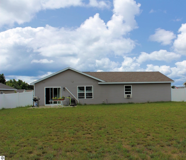 rear view of property featuring fence and a lawn