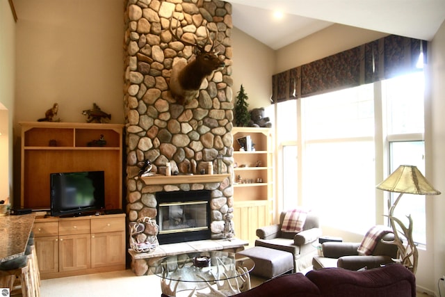 living room with lofted ceiling, a stone fireplace, and a wealth of natural light