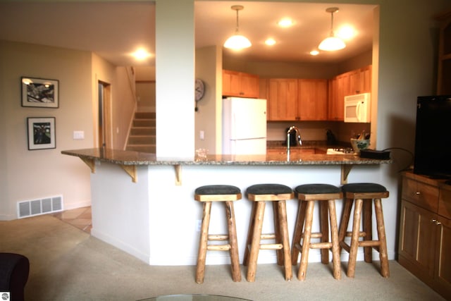 kitchen featuring kitchen peninsula, white appliances, stone counters, and hanging light fixtures