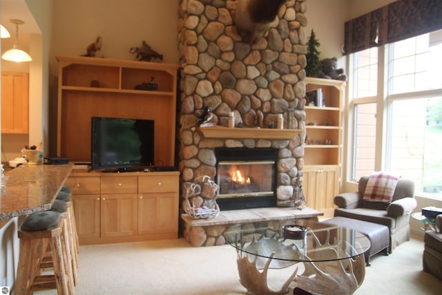 living room featuring a healthy amount of sunlight, light colored carpet, and a stone fireplace