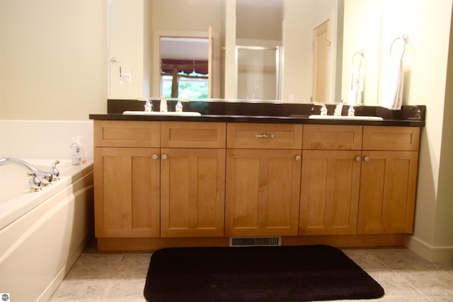 bathroom with a bath, double vanity, a sink, and visible vents