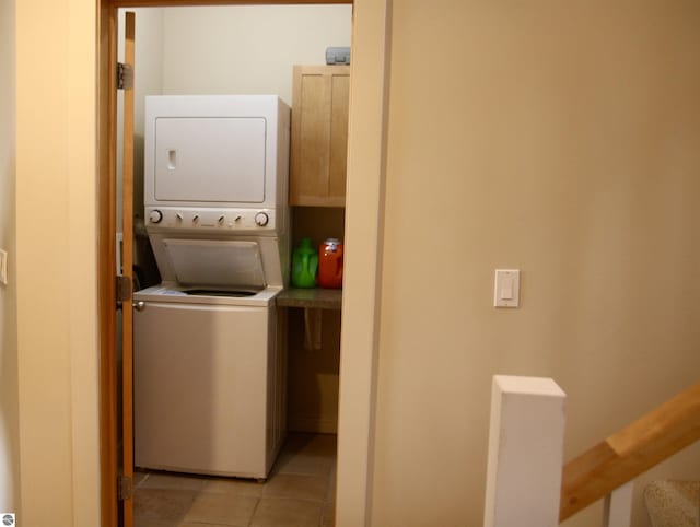 laundry area featuring light tile patterned floors, laundry area, and stacked washer and clothes dryer