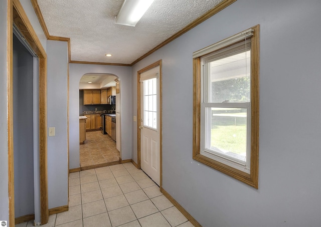 hallway featuring ornamental molding, a textured ceiling, and light tile patterned floors