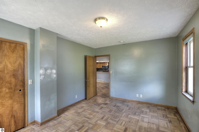 spare room featuring a textured ceiling and light parquet floors