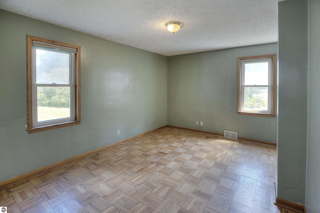 empty room featuring light parquet flooring and a textured ceiling