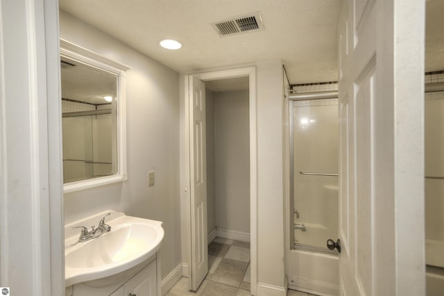 bathroom featuring vanity, a textured ceiling, and combined bath / shower with glass door