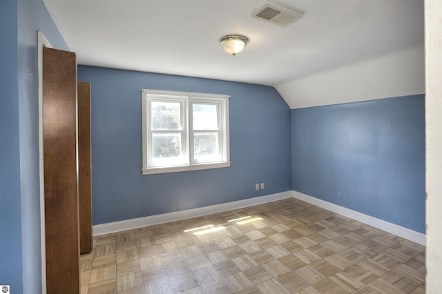 additional living space featuring light parquet flooring and vaulted ceiling