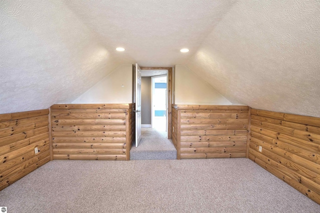 bonus room with lofted ceiling, carpet, rustic walls, and a textured ceiling