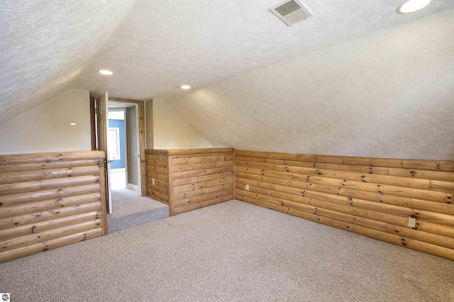 additional living space with vaulted ceiling, carpet floors, log walls, and a textured ceiling