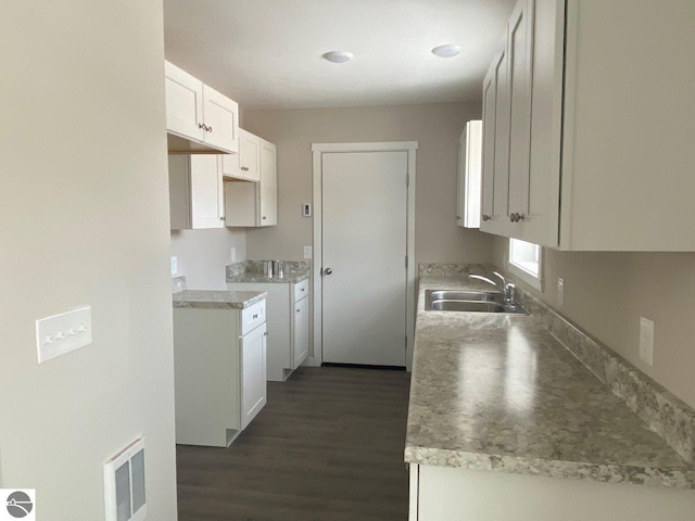 kitchen featuring visible vents, a sink, light countertops, white cabinetry, and dark wood-type flooring