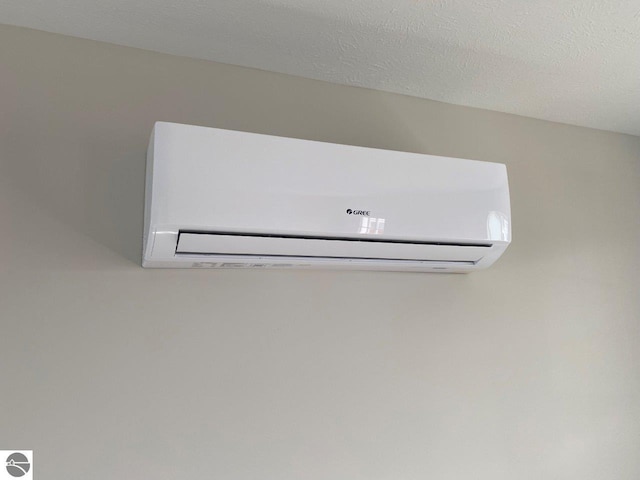 details featuring a wall mounted air conditioner and a textured ceiling