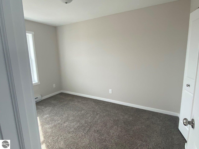 empty room with dark carpet, baseboard heating, and baseboards
