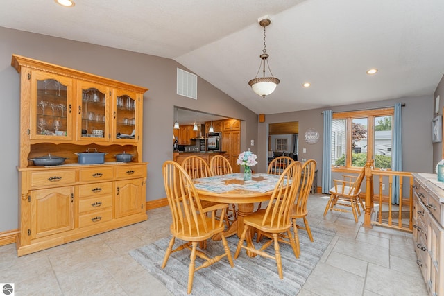 tiled dining space with lofted ceiling