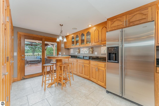 kitchen with dark stone countertops, hanging light fixtures, and stainless steel fridge