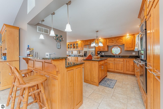 kitchen with appliances with stainless steel finishes, a breakfast bar, dark stone counters, hanging light fixtures, and a center island