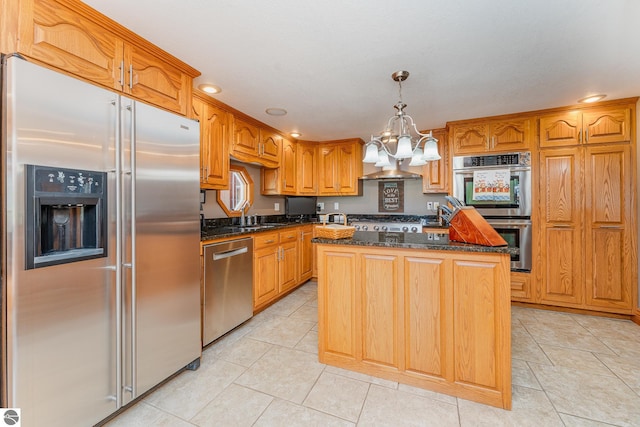 kitchen with pendant lighting, stainless steel appliances, a center island, and dark stone countertops