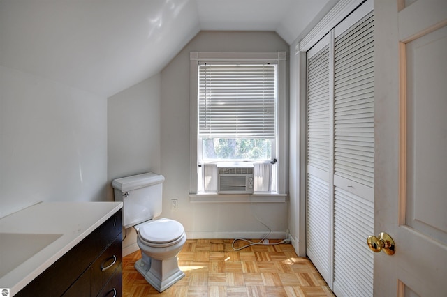 bathroom featuring parquet floors, lofted ceiling, toilet, and vanity