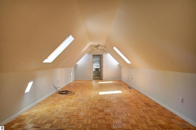 additional living space featuring lofted ceiling with skylight and light parquet flooring