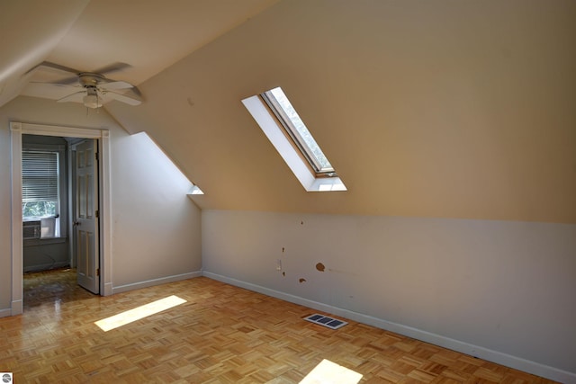 additional living space featuring light parquet floors, vaulted ceiling with skylight, and ceiling fan