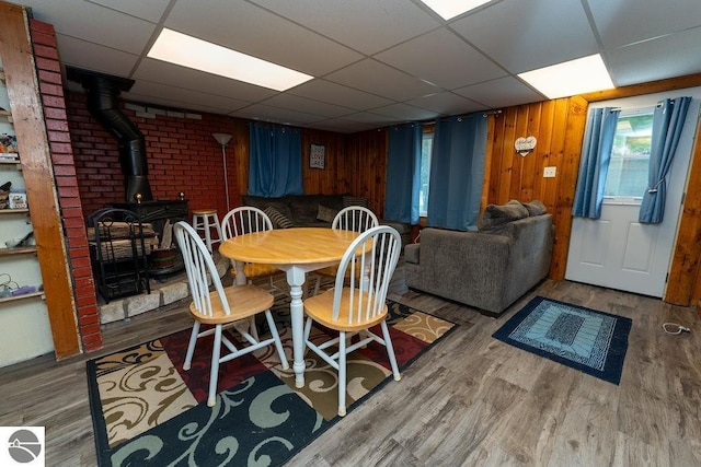 dining space featuring light wood-type flooring, wooden walls, and a wood stove